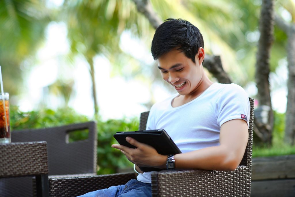 asian man sitting looking at ipad